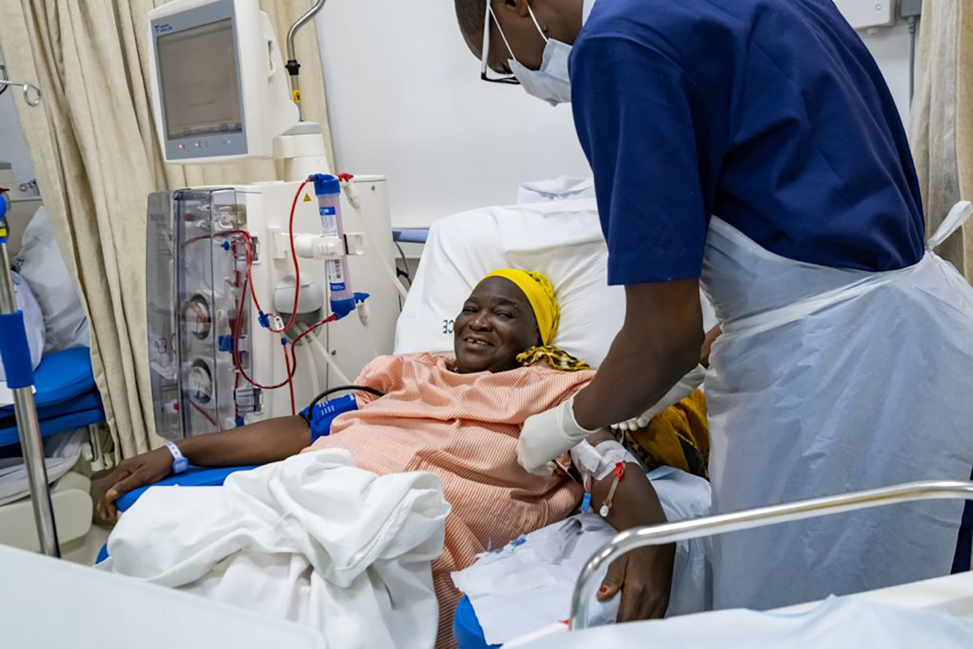A patient on a hospital bed receiving dialysis treatment from a health care worker